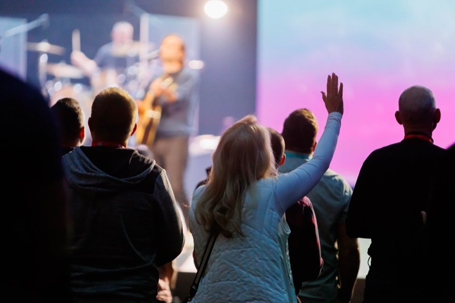 Attendees worshipping with hands raised
